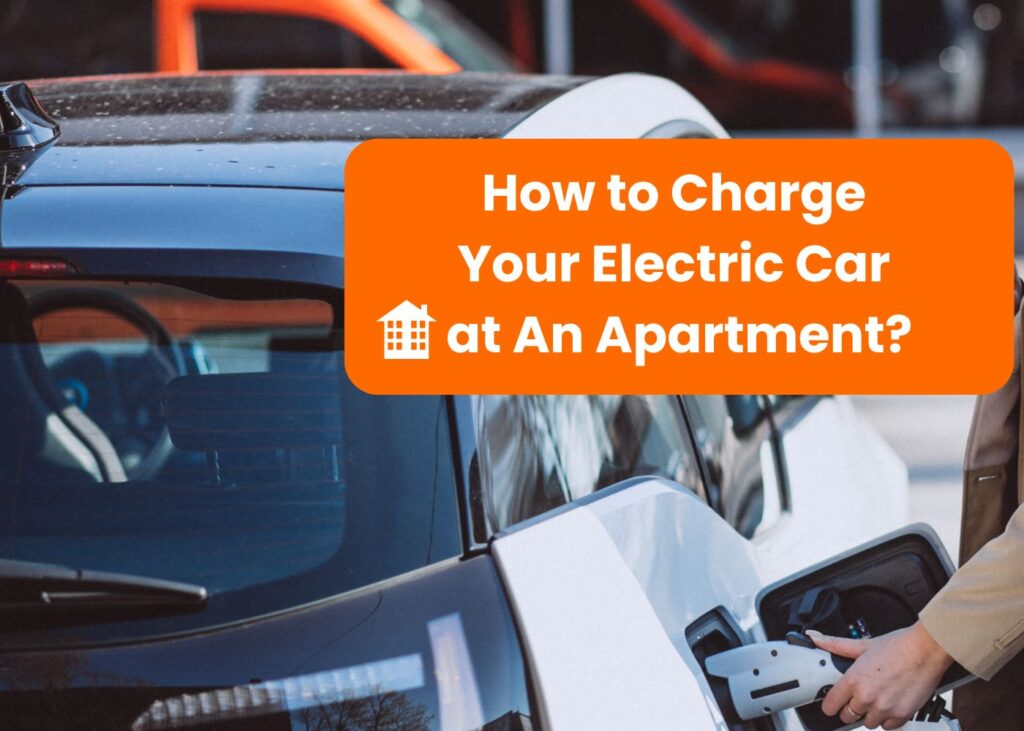 A person is charging an electric car at an apartment complex. The image shows the charging cable being plugged into the car with a clear view of the car's rear and the charging station. The text on the image asks how to charge an electric car in an apartment, highlighting the challenge of finding charging options in such living situations.